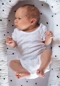 Νεογέννητο μωρό ξαπλωμένο με τα ποδαράκια ανοιχτά και τα γόνατα λυγισμένα