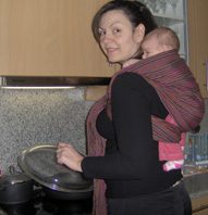 Mom cooking with the baby in a rucksack carry