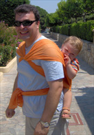 Vasilis, on his dad's back, in a wrap carrier