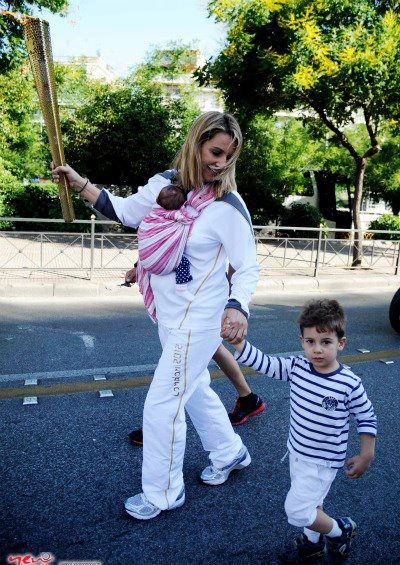 Sofia Bekatorou with the Olympic flame and her baby in an Asteraki Sling