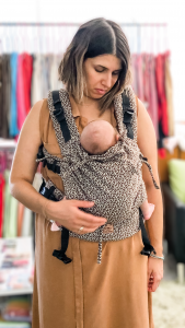  /></a>
<div>In fact, in the beginning, it’s almost necessary to keep things simple. If your mind is focused on how to cover up, you won’t be able to focus on helping your baby latch properly.
That feeling of “having free hands to multitask” doesn’t apply when breastfeeding.
Wearing your baby in a soft carrier helps you position them without needing pillows, lets you support your breast properly, and helps you feel more at ease.
But there’s a difference between being able to stand up to answer the door or grab a glass of water — and trying to complete full tasks while feeding.
And never — <b>never</b> — let go of your baby’s head during breastfeeding. <b>The baby’s head should never be inside the sling during feeding</b>. It should always be in your hand — you’re in control.</div>
<div>Note: When we think of breastfeeding, we often imagine a baby lying in mom’s arms. That’s how we’re taught — because without a carrier, upright feeding would take a hundred hands or a hundred pillows!
But babies actually breastfeed very well in an upright position (and let’s face it — we eat better sitting up too).
Upright feeding improves digestion, reduces reflux, and helps with spit-up.
From what I’ve seen, most moms who try upright feeding rarely go back to laid-back positions — even in a ring sling, which allows both.</div>
<div>Watch this video of a <b>newborn breastfeeding in a mei tai carrier:</b></div>
<iframe title=