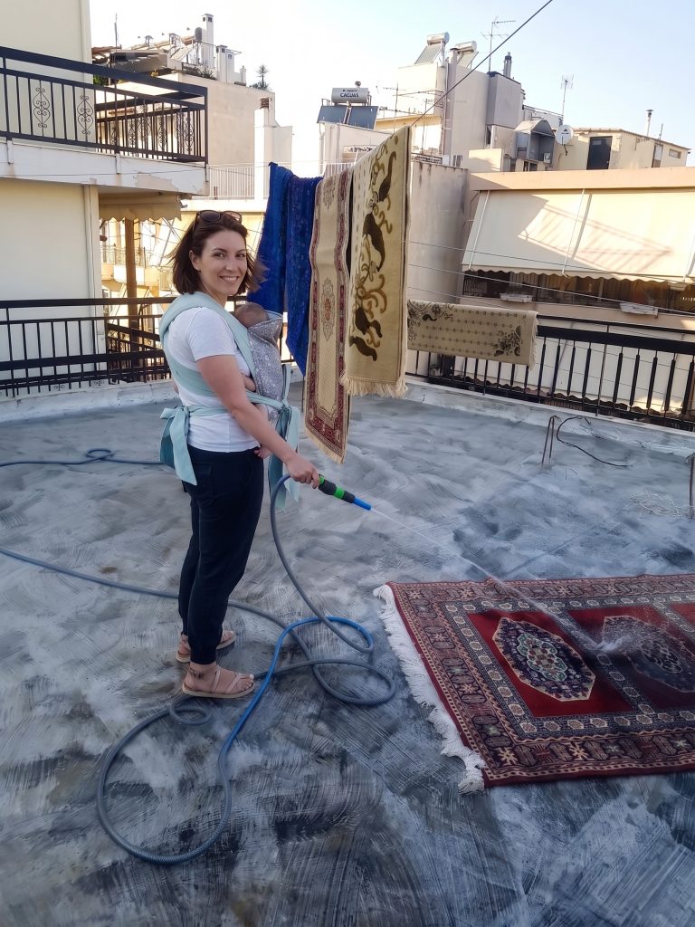 Μαμά καθαρίζει χαλί με το μωρό σε mei tai