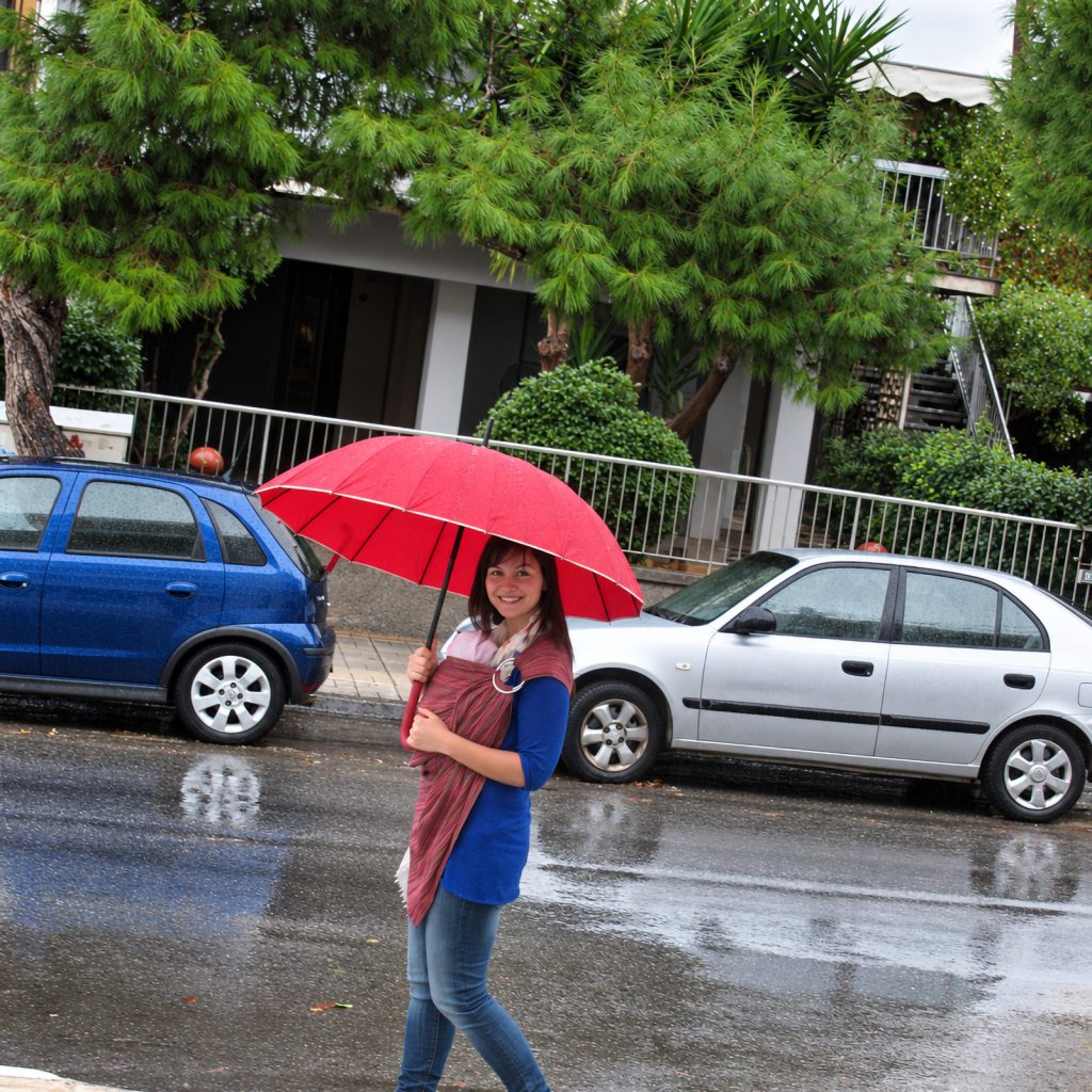 Baby in a sling under an umbrella while it's raining