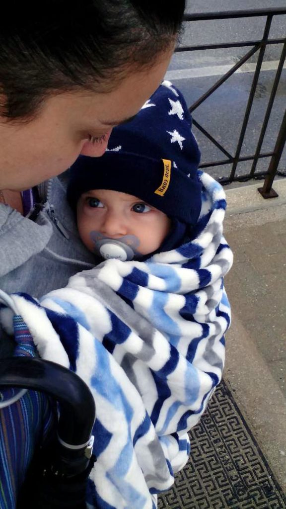 Baby in a carrier on a rainy day, tucked under a little blanket